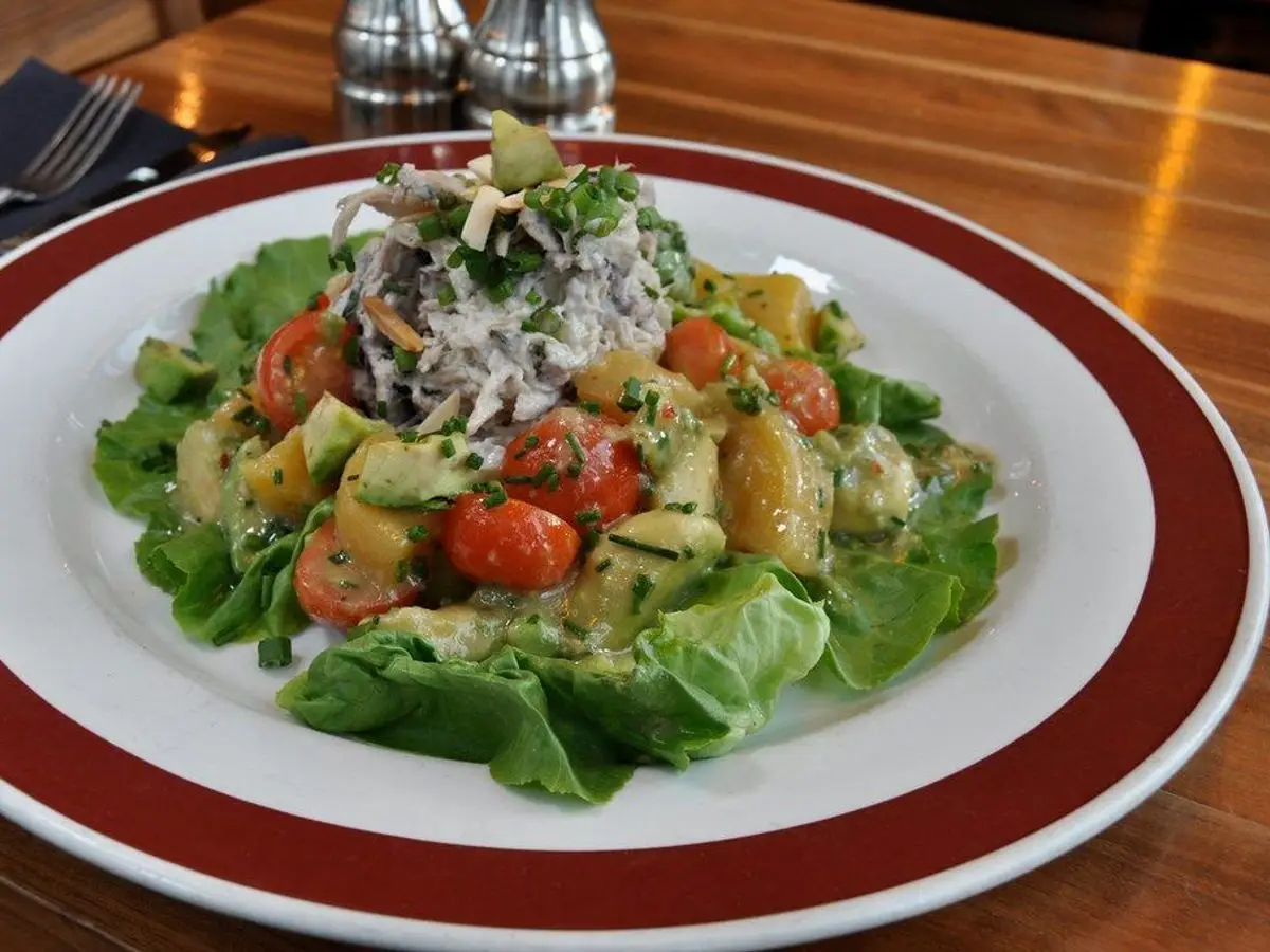 Plato con ensalada de lechuga, tomate cherry y patata troceada sobre un mantel de madera