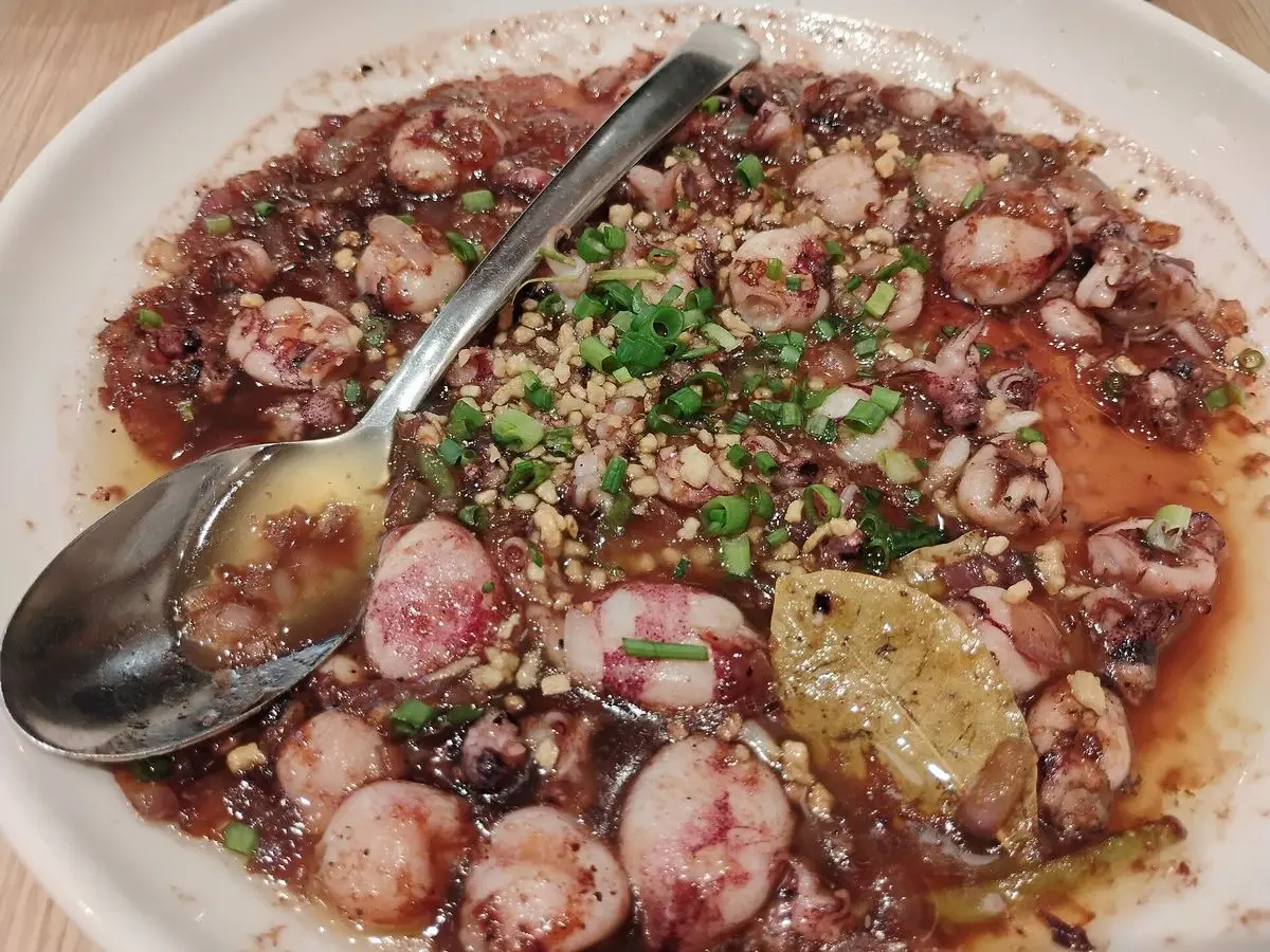 Plato con chipirones troceados en salsa con perejil picado y una cuchara
