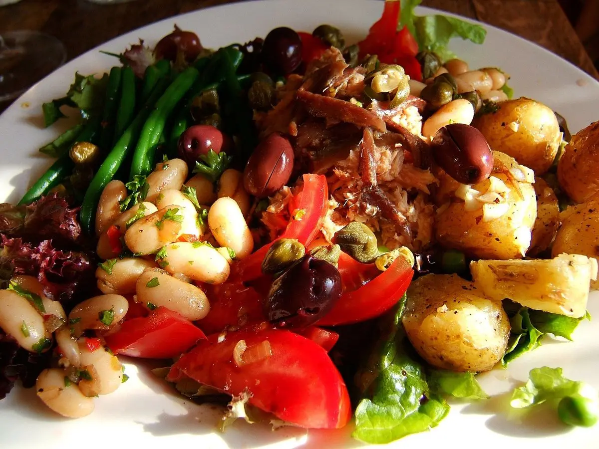 Plato de ensalada templada con alubias blancas, patatas, judías verdes, tomate y aceitunas