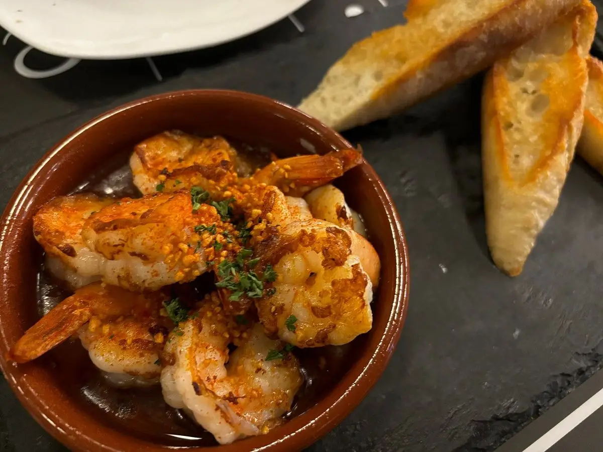 Cazuela de barro con gambas al ajillo, hierbas y pan tostado al lado