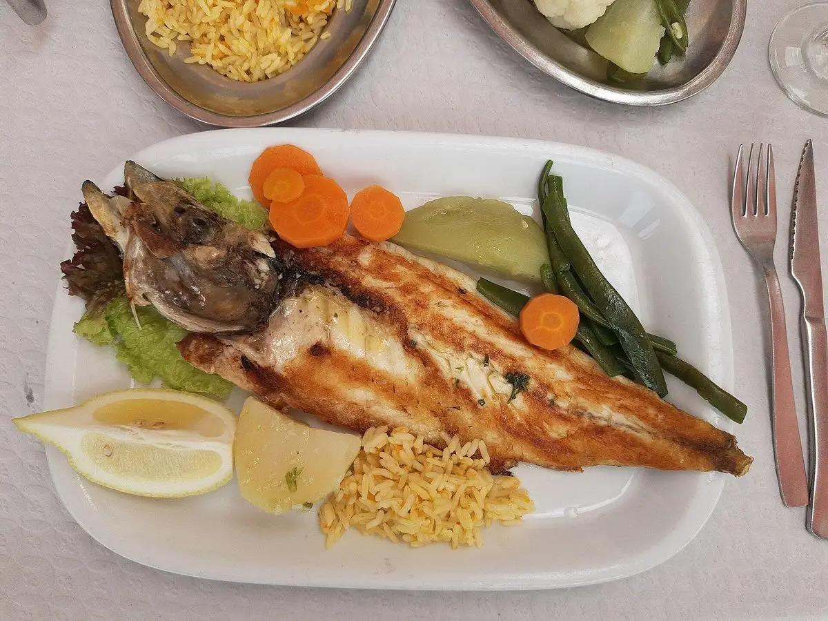 Bandeja con pescado a la plancha, judías verdes, zanahoria, limón y guarnición
