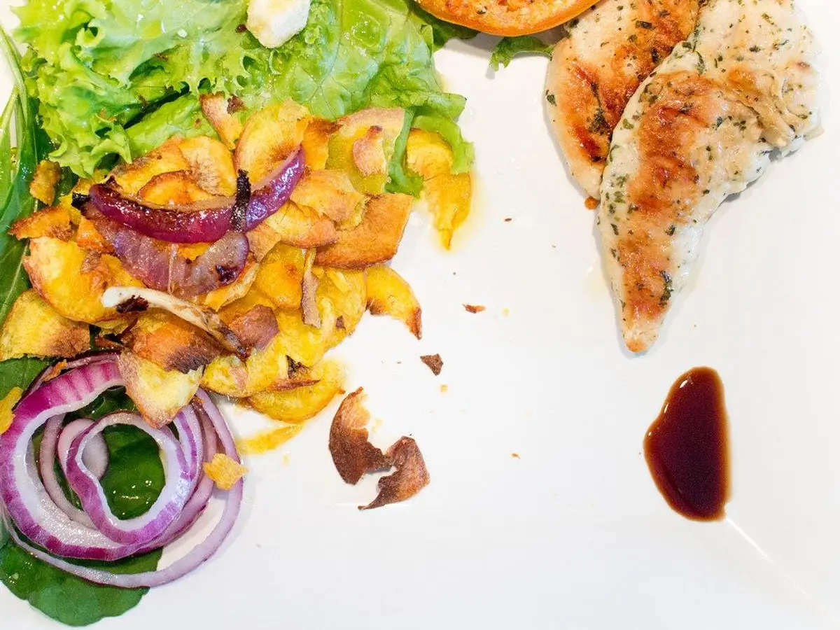 Plato blanco con pechuga de pollo a la plancha en tiras, patata asada, pimientos y lechuga