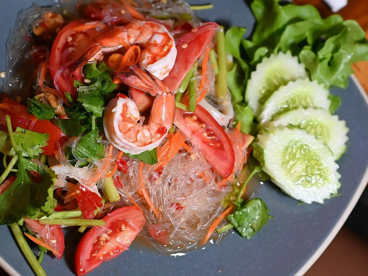 Ensalada de fideos de cristal con langostinos, pepino, tomate y hierbas frescas en un plato