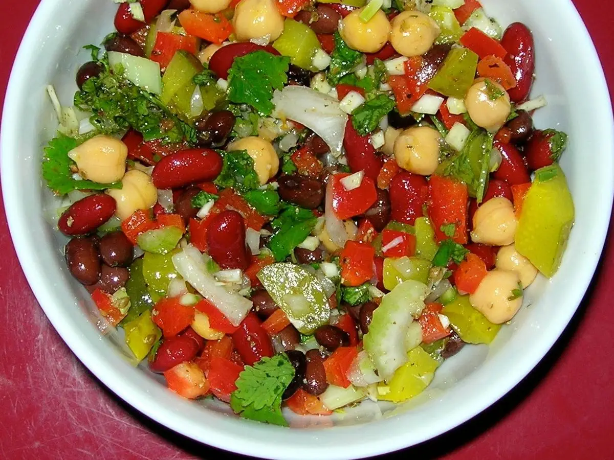 Cuenco blanco de ensalada de legumbres con garbanzos, alubias rojas, pimiento y pepino