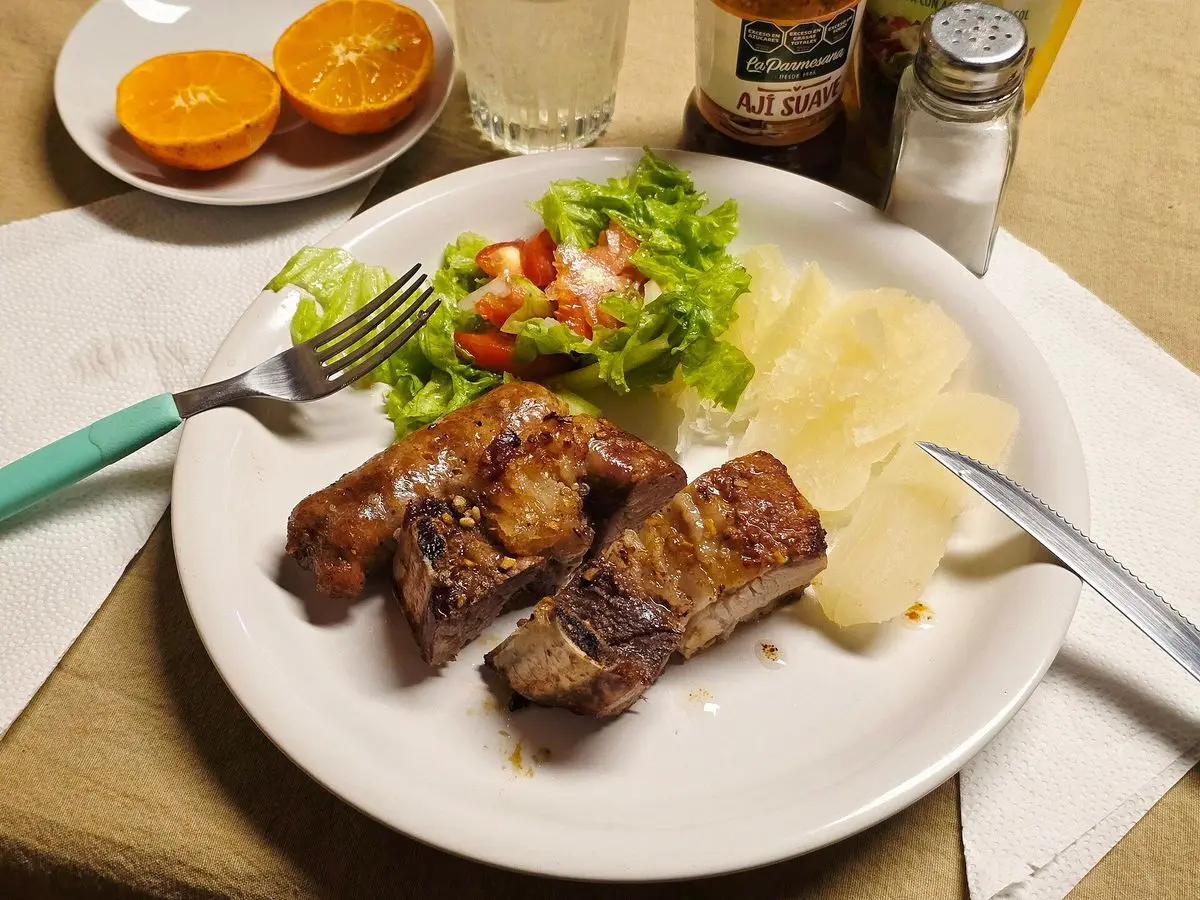 Carne a la parrilla en plato blanco con ensalada de lechuga y tomate y patata cocida