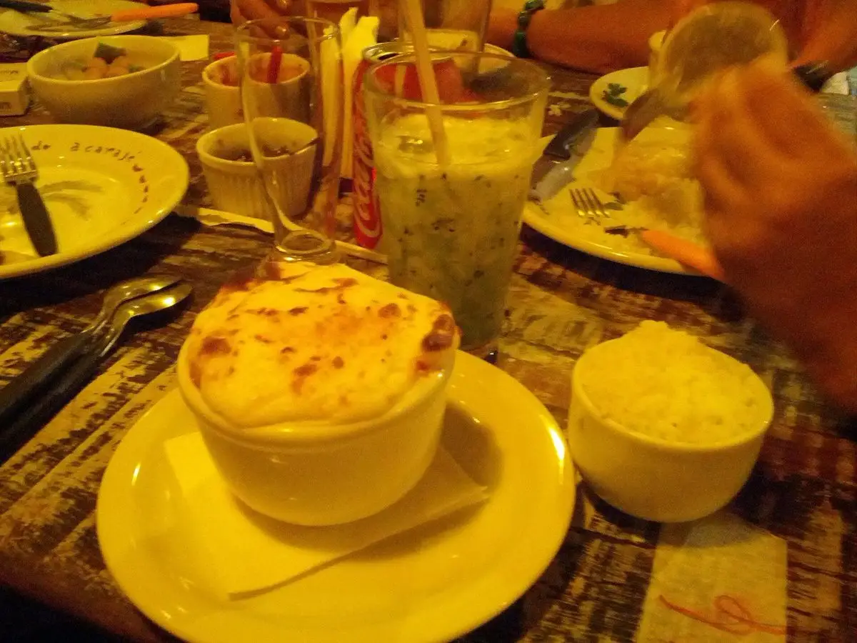 Cuenco de puré gratinado dorado con relleno escondido, servido en una mesa con arroz y bebida