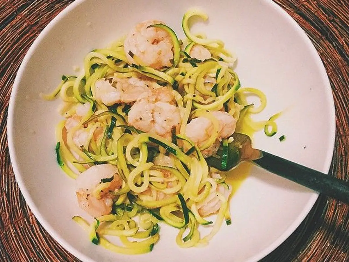 Espaguetis de calabacín con gambas salteadas en aceite en un cuenco blanco