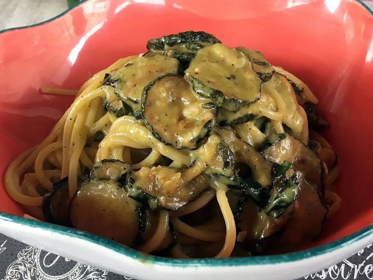 Espaguetis con rodajas de calabacín y queso cremoso en un cuenco rojo