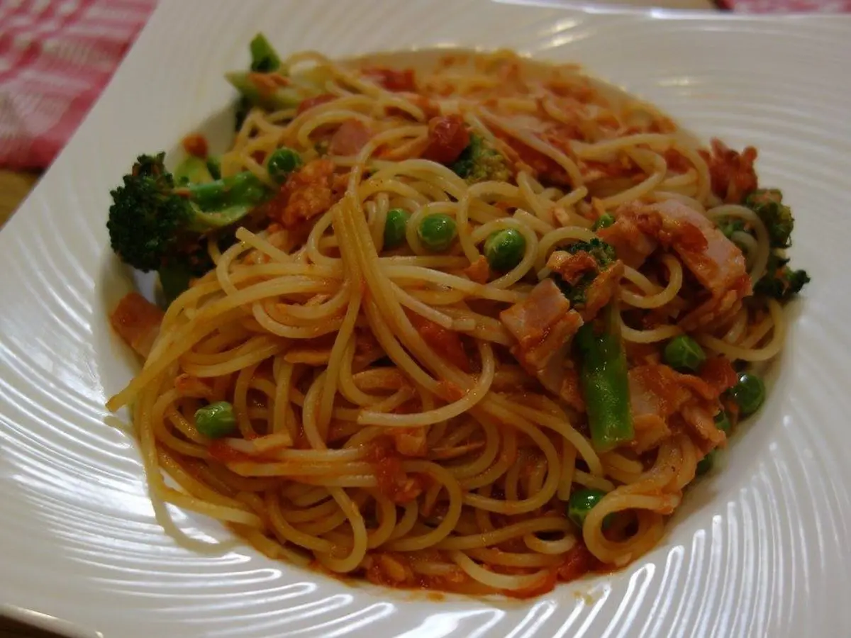 Espaguetis con atún, brócoli y salsa de tomate en un plato cuadrado blanco