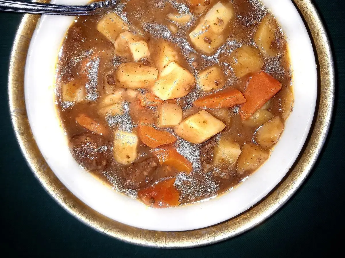 Plato hondo de estofado de ternera con patata y zanahoria en cubos en salsa oscura