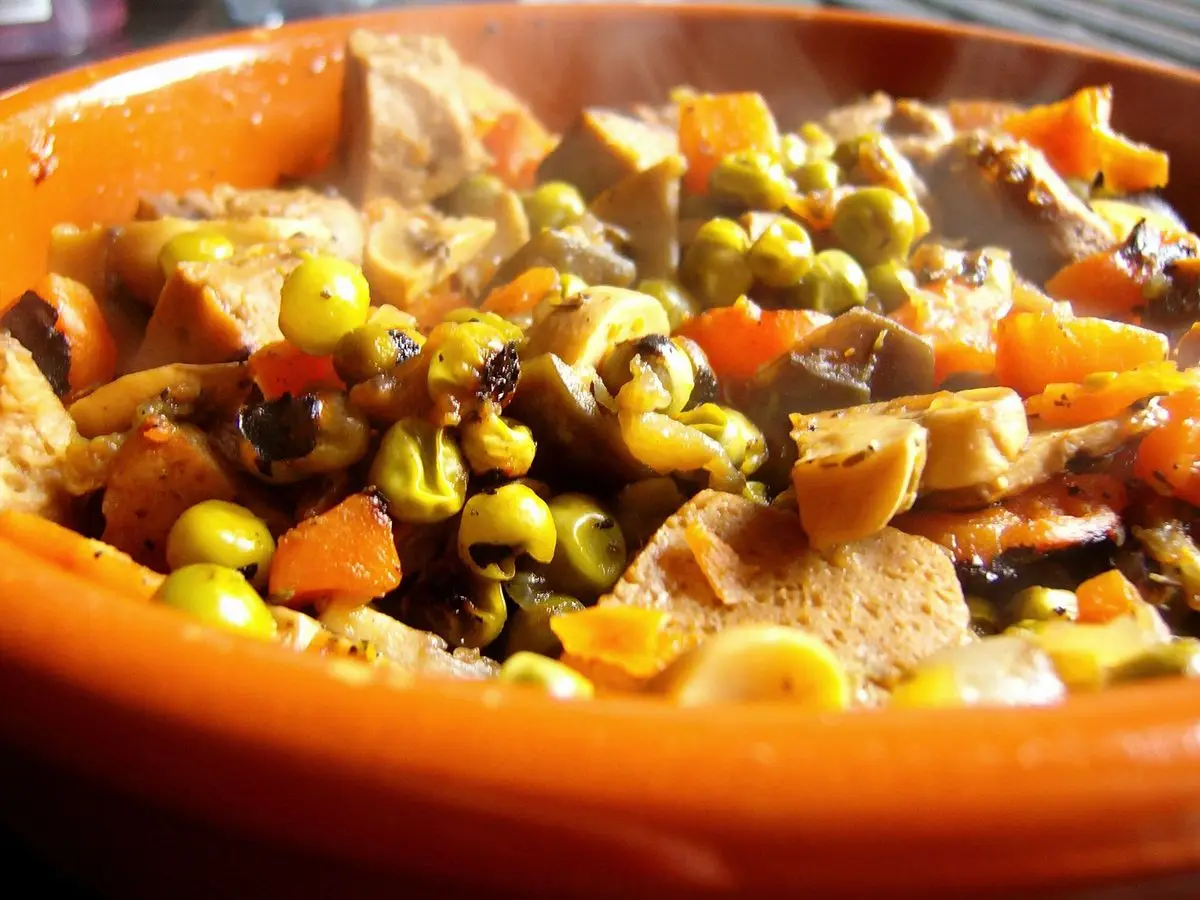 Cazuela naranja de estofado de seitán con zanahoria, guisantes y verduras troceadas