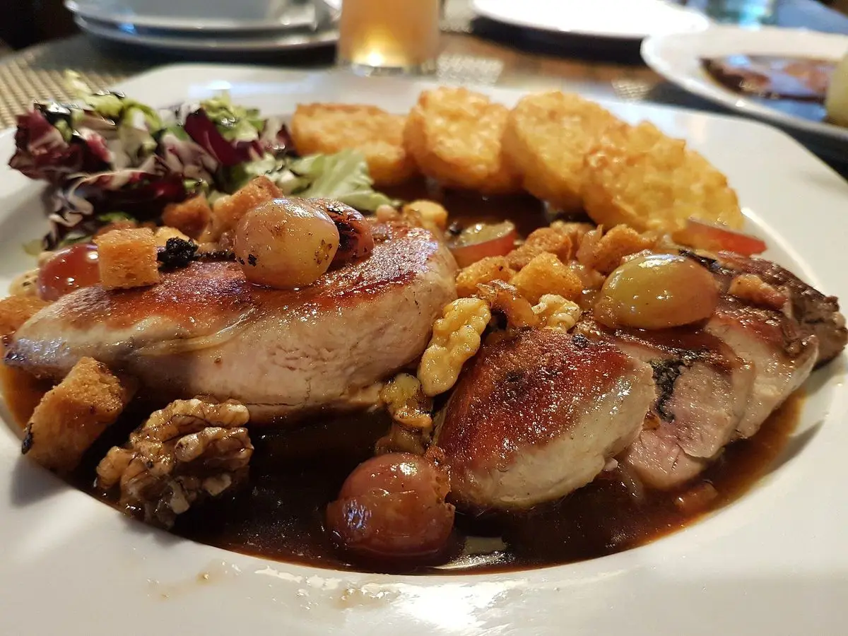 Pechuga de faisán asada con salsa, nueces, castañas y uvas, acompañada de patata dorada