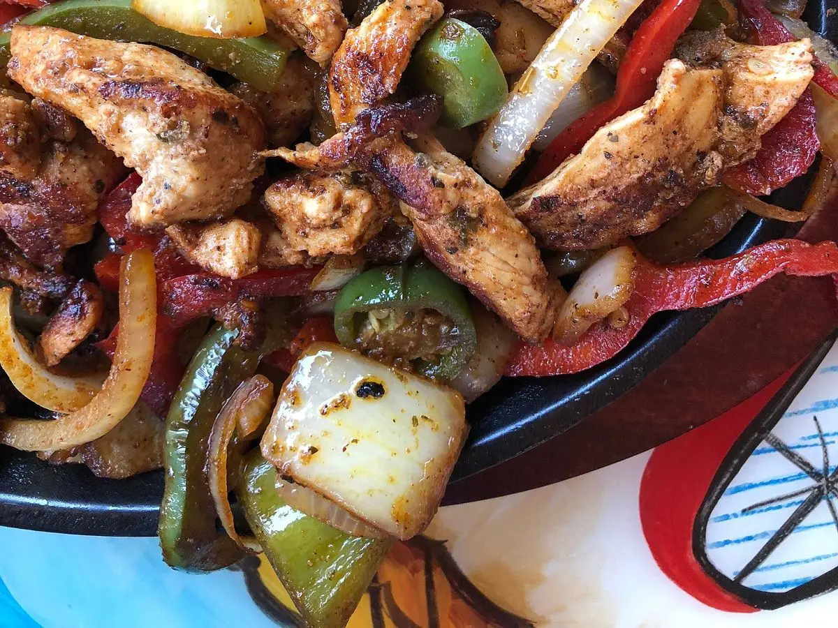 Tiras de pollo salteadas con pimientos rojos y verdes y cebolla