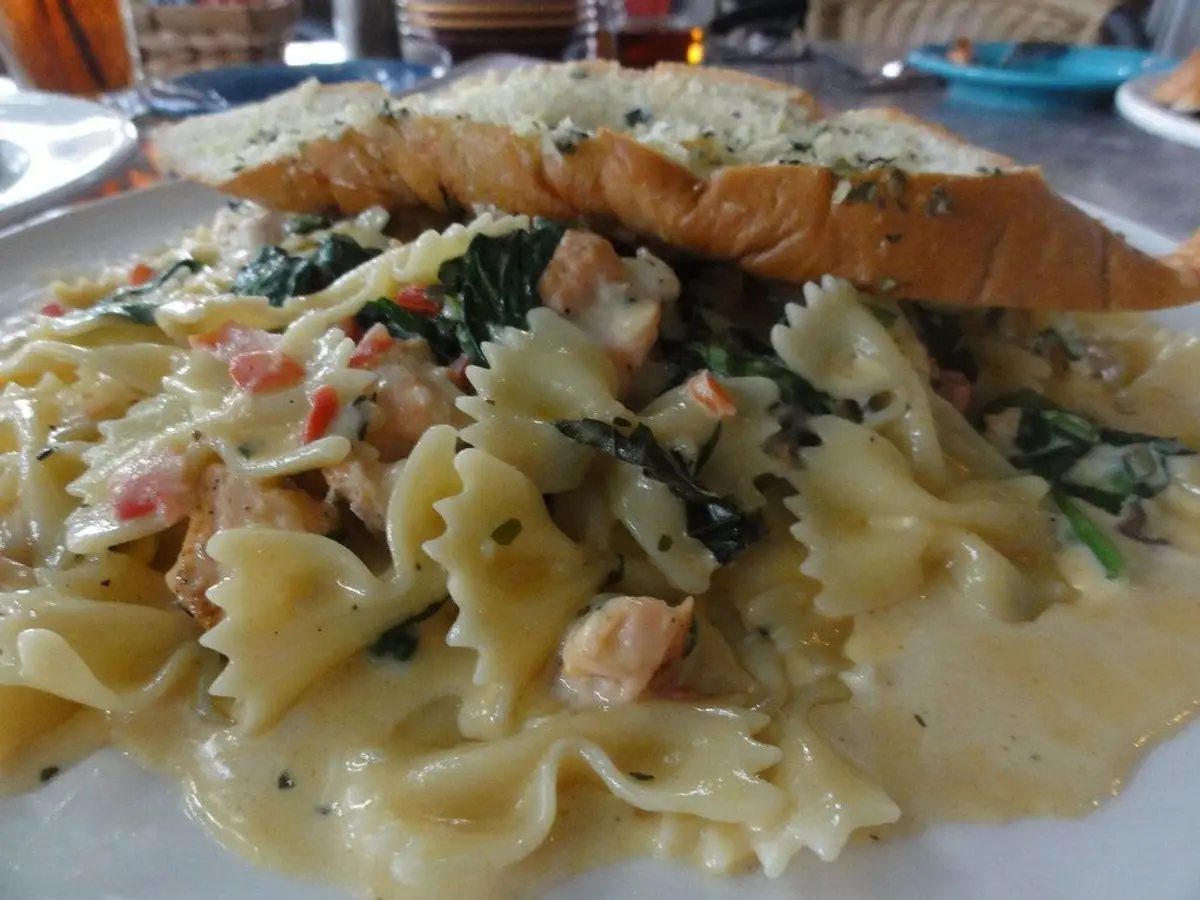 Pasta farfalle en salsa cremosa con espinacas y filete de salmón con costra encima