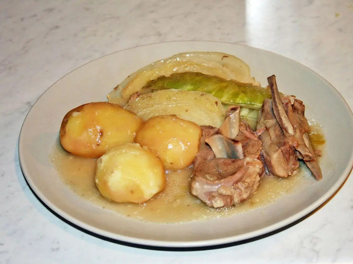 Plato con cordero cocido, col y patatas hervidas en caldo claro