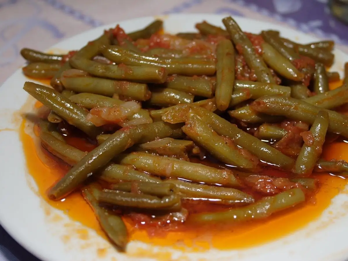 Plato blanco con judías verdes guisadas en salsa de tomate y aceite