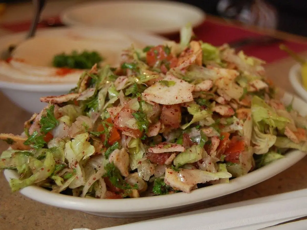 Fuente de ensalada fattoush con lechuga, tomate y trozos de pan crujiente