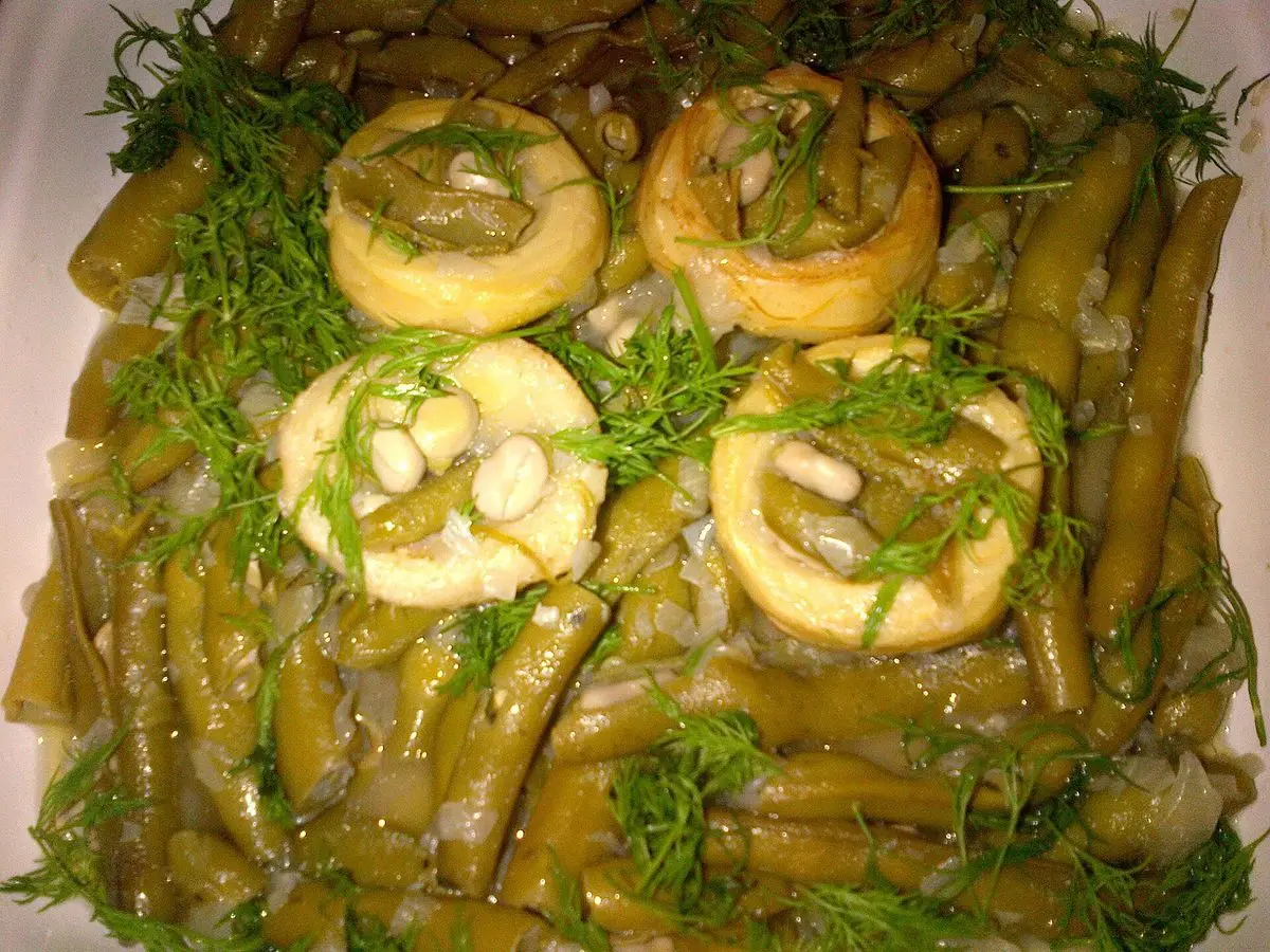 Cazuela de vainas verdes con alcachofas pequeñas rellenas y eneldo fresco