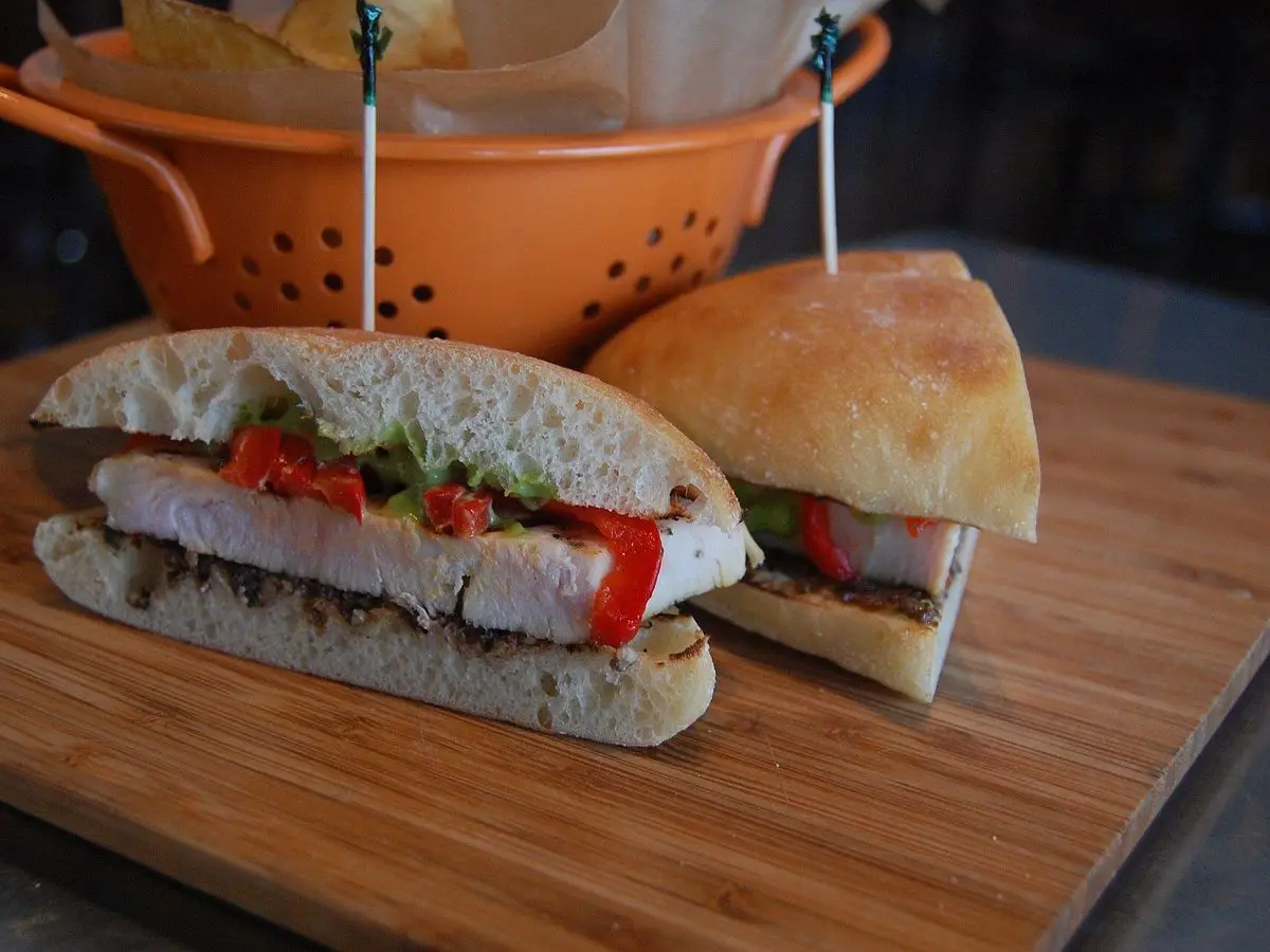 Bocadillo de pechuga de pavo en lonchas con tomate y lechuga sobre una tabla de madera