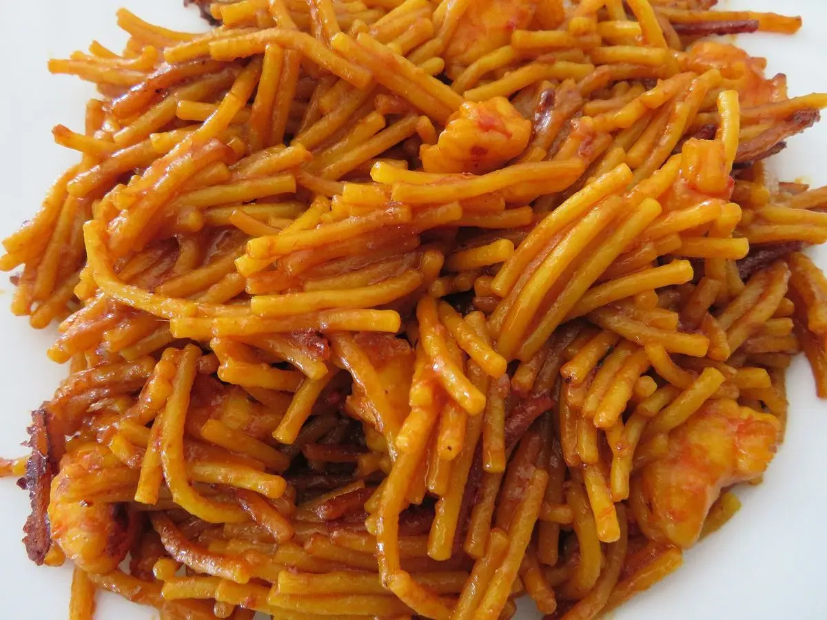Plato de fideos dorados cocinados al estilo de la fideuá sobre un plato blanco