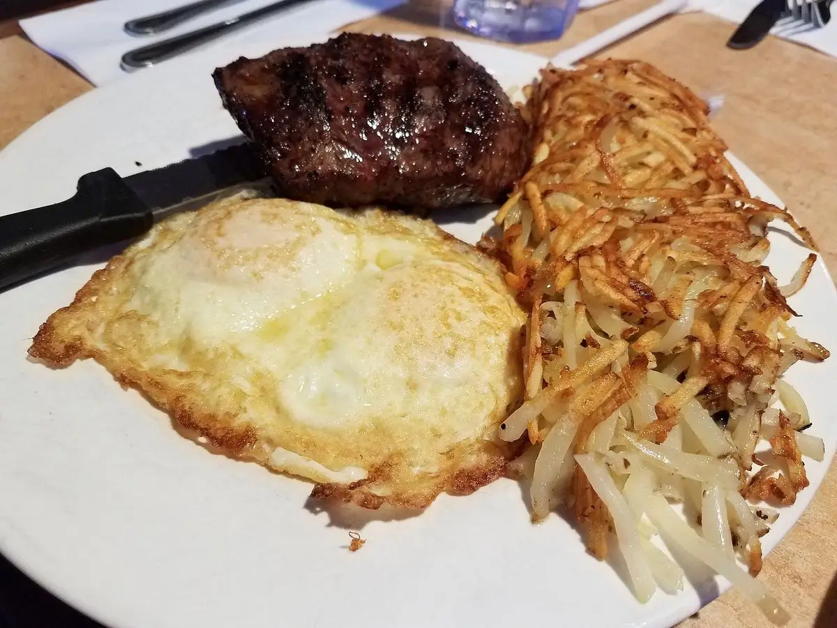 Plato con filete de ternera a la plancha, huevo frito y patata rallada dorada
