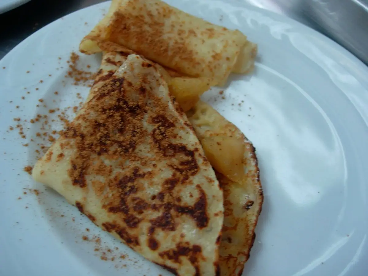Plato blanco con filloas dobladas rellenas y espolvoreadas con azúcar y canela