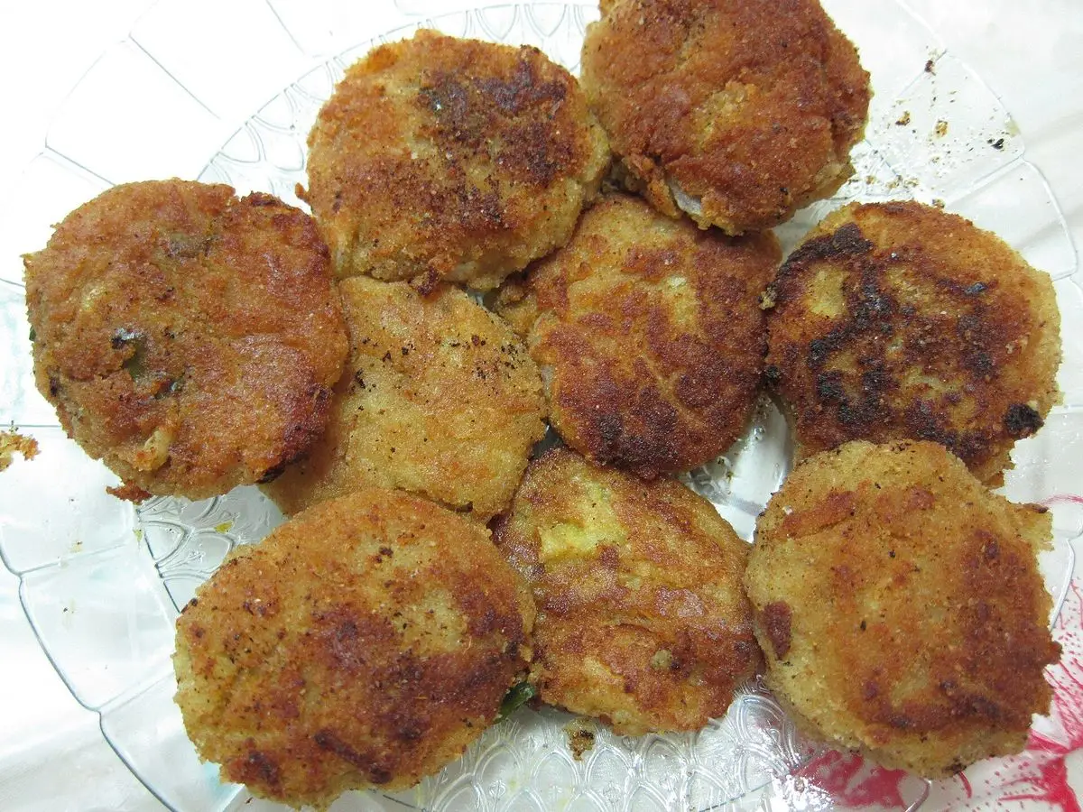Croquetas planas de pescado doradas y crujientes servidas en un plato blanco