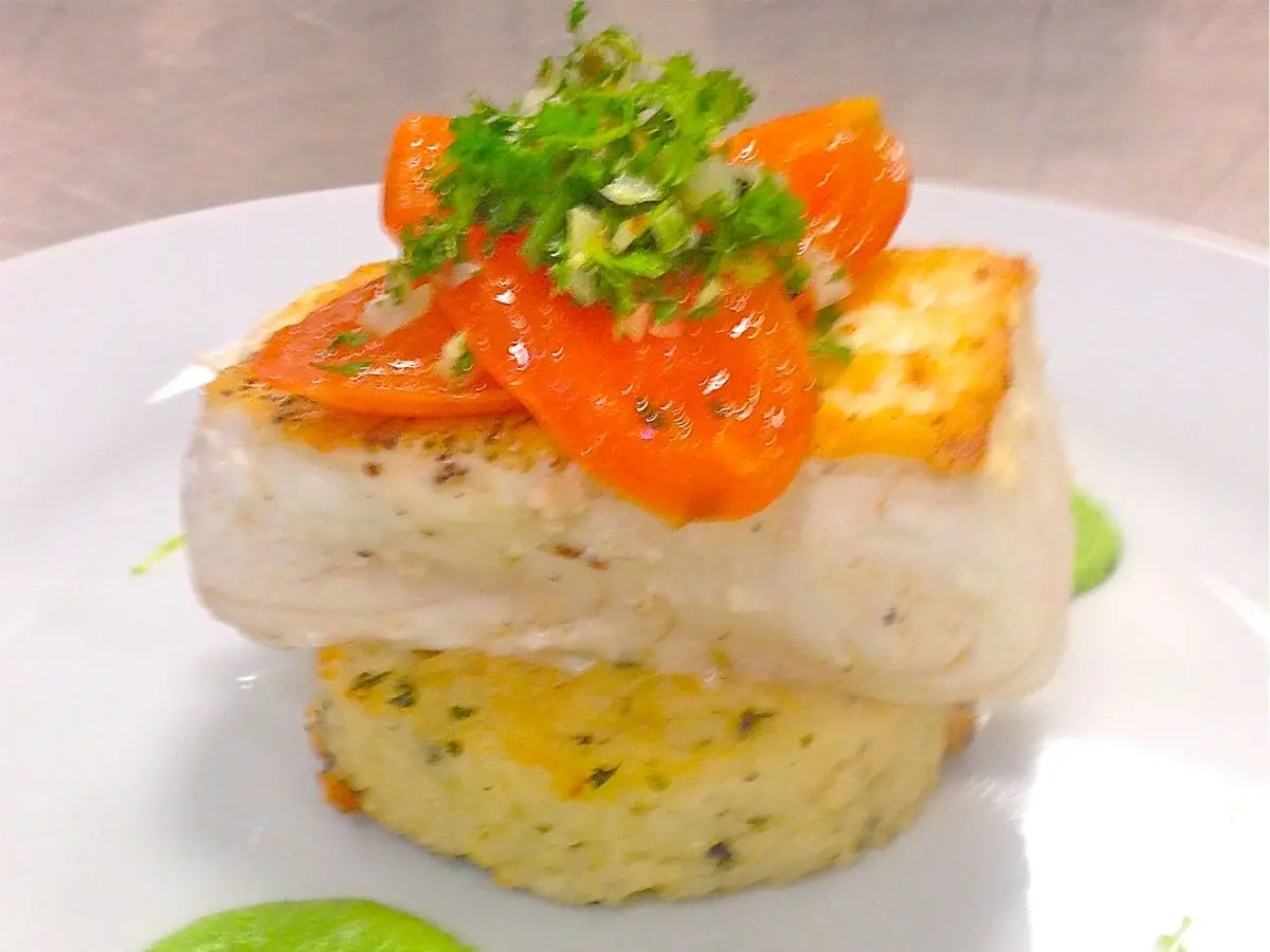 Lomo de pescado blanco a la plancha sobre un pastel de patata, con tomate y hierbas y crema verde de guisantes
