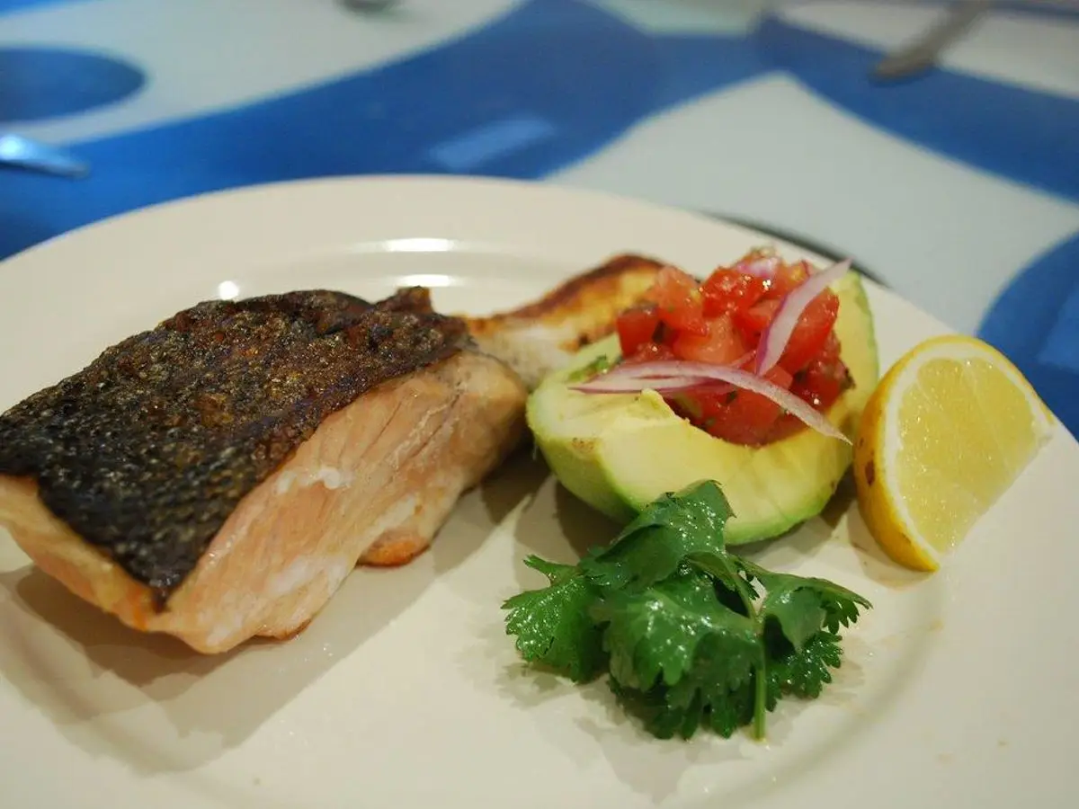 Filete de pescado a la plancha con piel crujiente, aguacate, salsa de tomate y cebolla morada, cilantro y lima