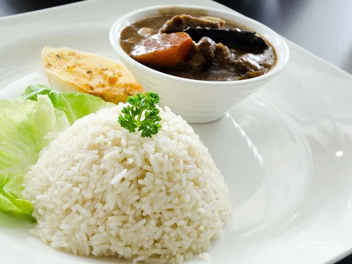 Cuenco de guiso de cordero con arroz blanco en forma de cúpula, lechuga y huevo duro