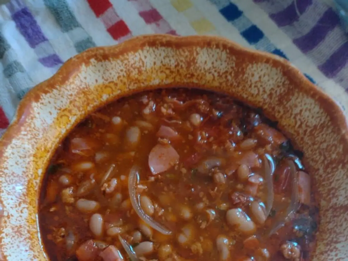 Cazuela de barro con frijoles charros en caldo de tomate con cebolla y embutido