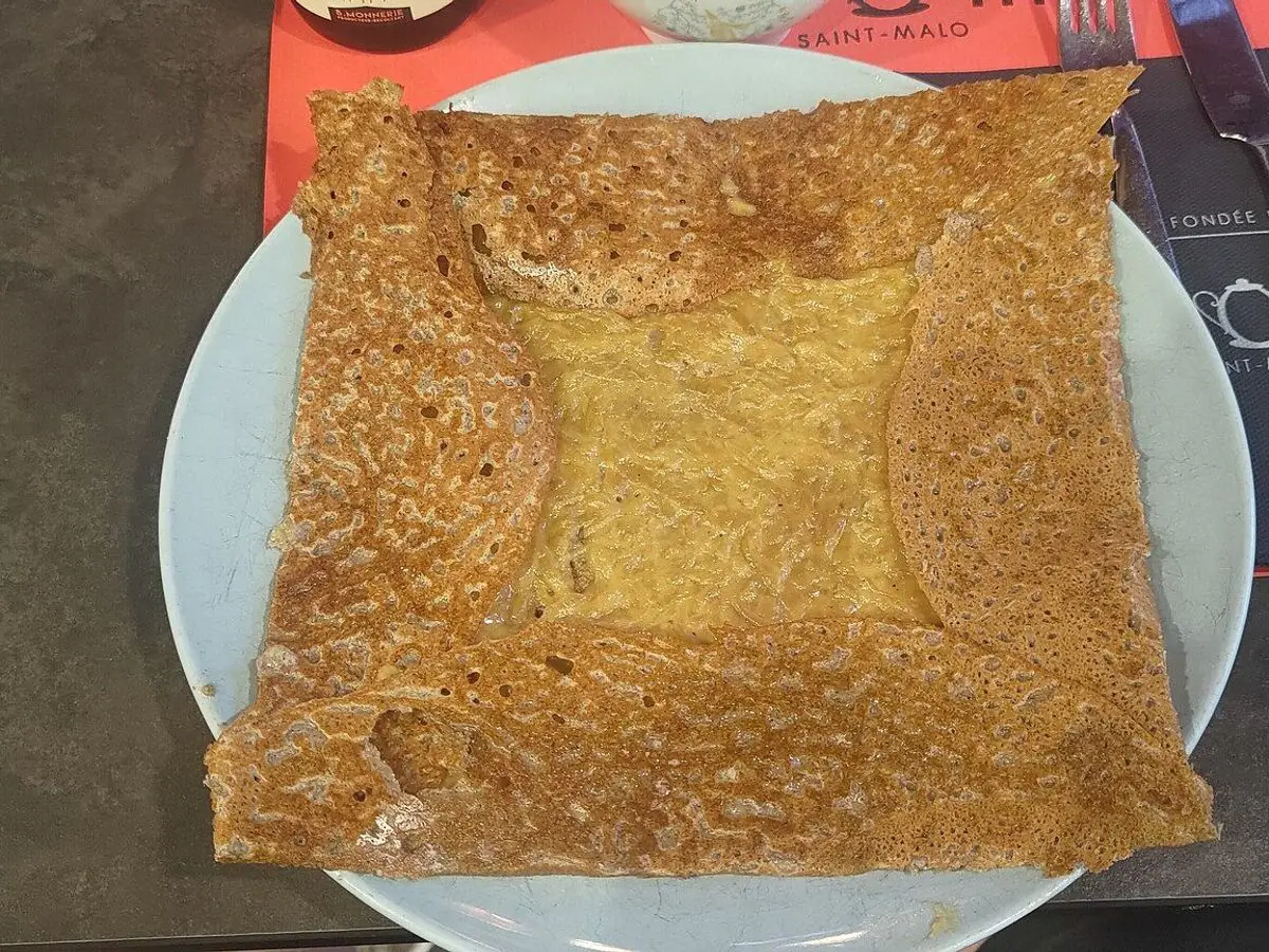 Galette bretona de trigo sarraceno doblada en cuadrado con relleno cremoso en un plato
