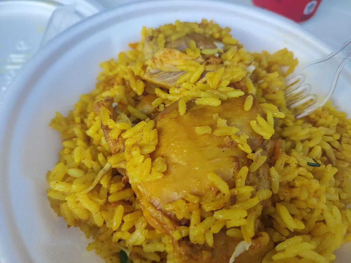 Plato de arroz amarillo con cúrcuma y pollo guisado con maíz