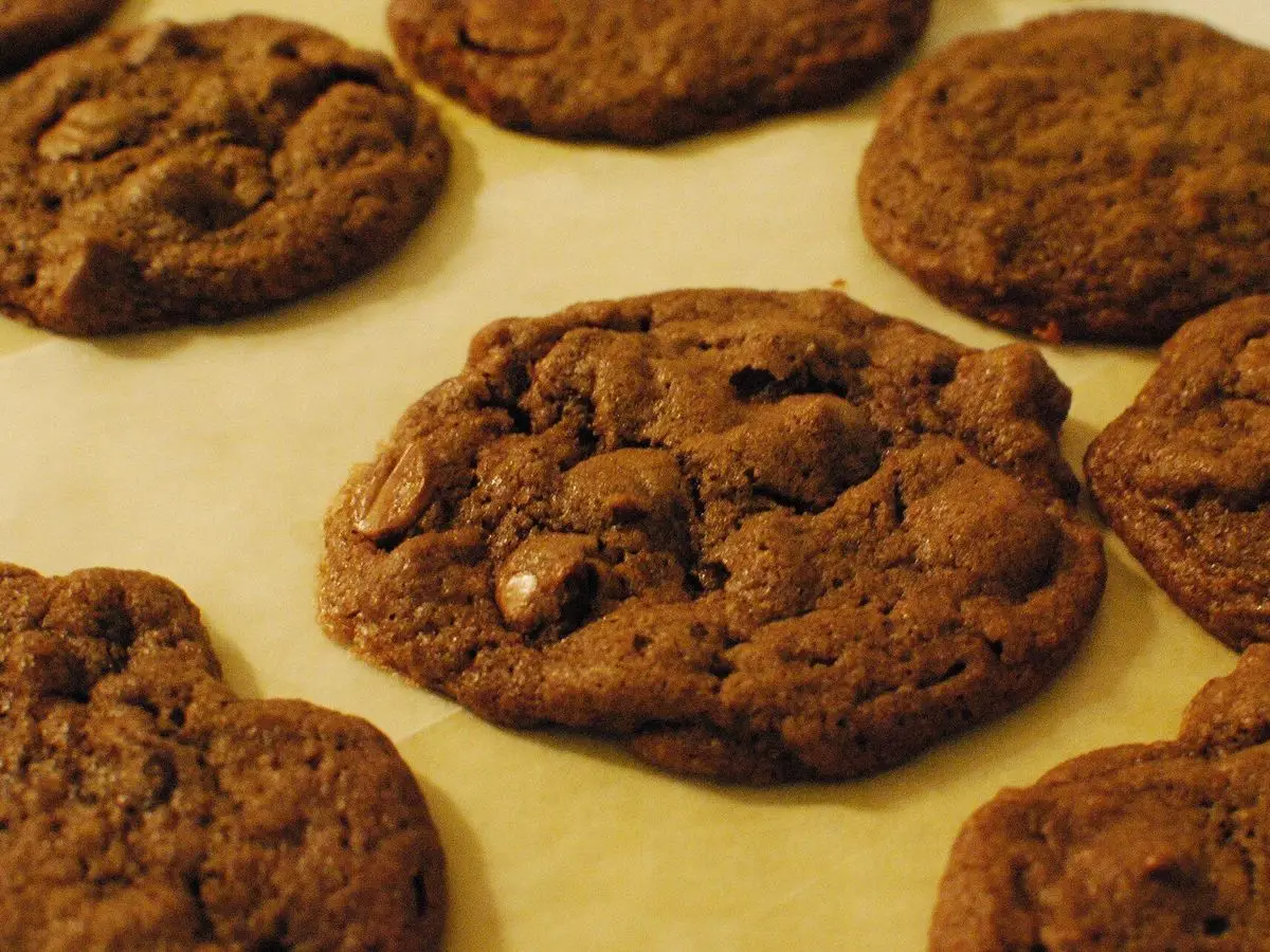 Galletas redondas de chocolate con trozos de chocolate recién horneadas sobre papel de horno