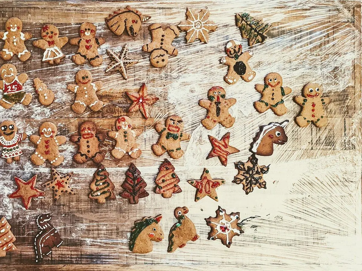 Muchas galletas de jengibre con formas de muñeco, estrella y árbol sobre una mesa de madera