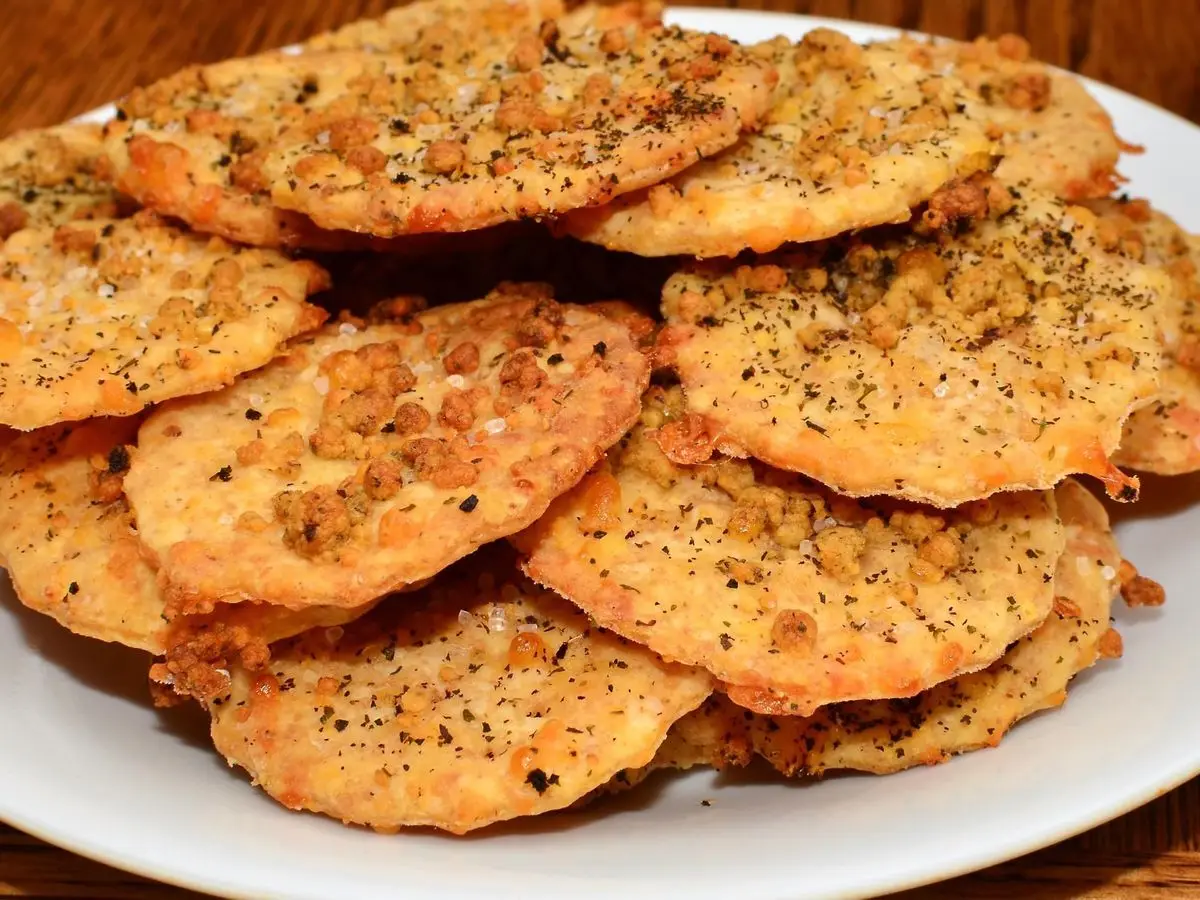 Plato blanco con crujientes galletas de queso doradas espolvoreadas de pimienta