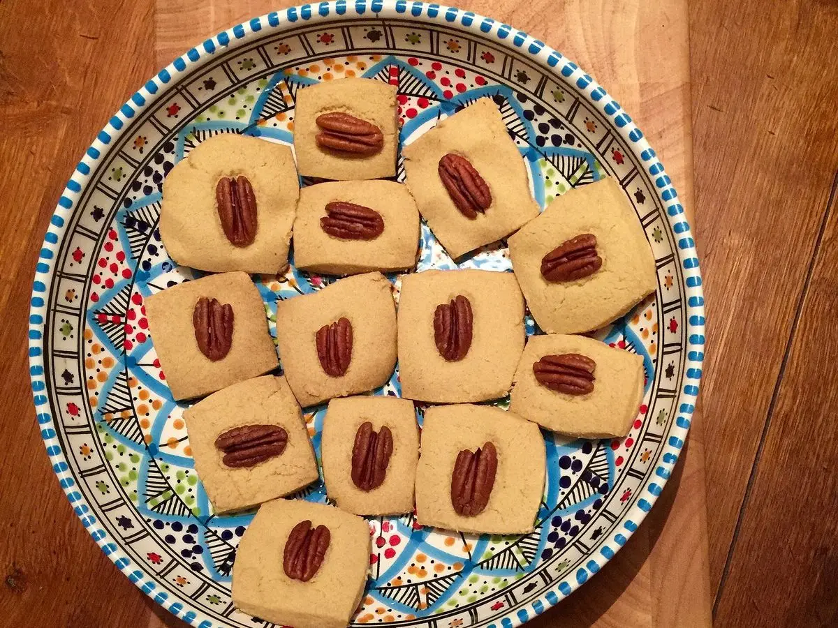 Plato decorado con galletas cuadradas de tahini coronadas con una nuez pecana cada una
