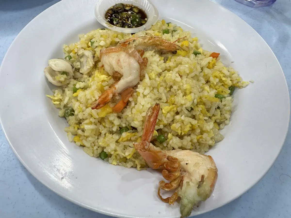 Arroz salteado con gambas, huevo y verduras en un plato blanco