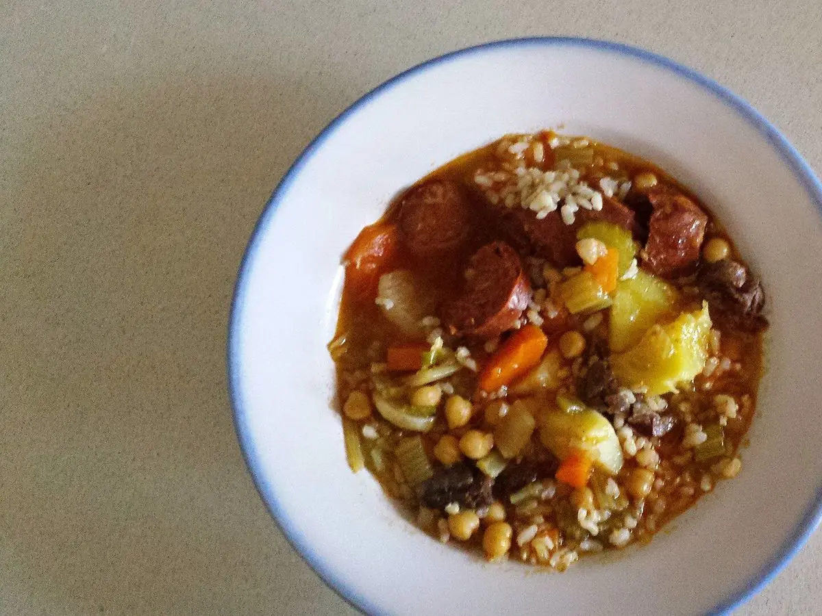 Plato hondo de potaje de garbanzos con chorizo, carne, patata, zanahoria y algo de arroz