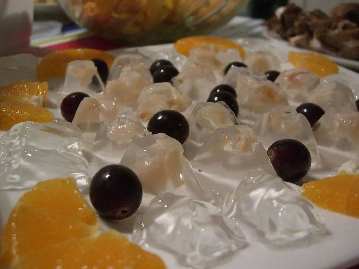 Cubos de gelatina transparente con lichis y gajos de naranja en un plato