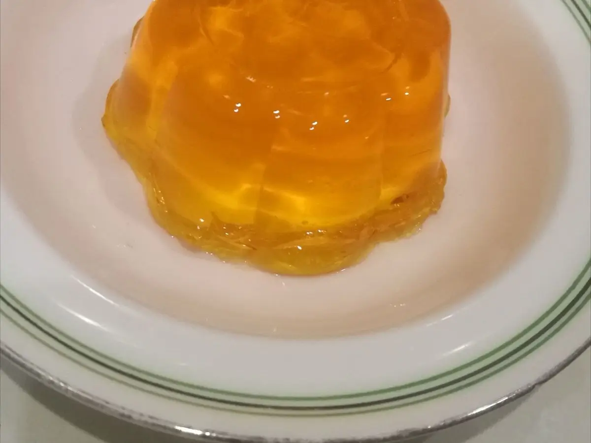 Gelatina anaranjada desmoldada sobre un plato blanco con borde verde