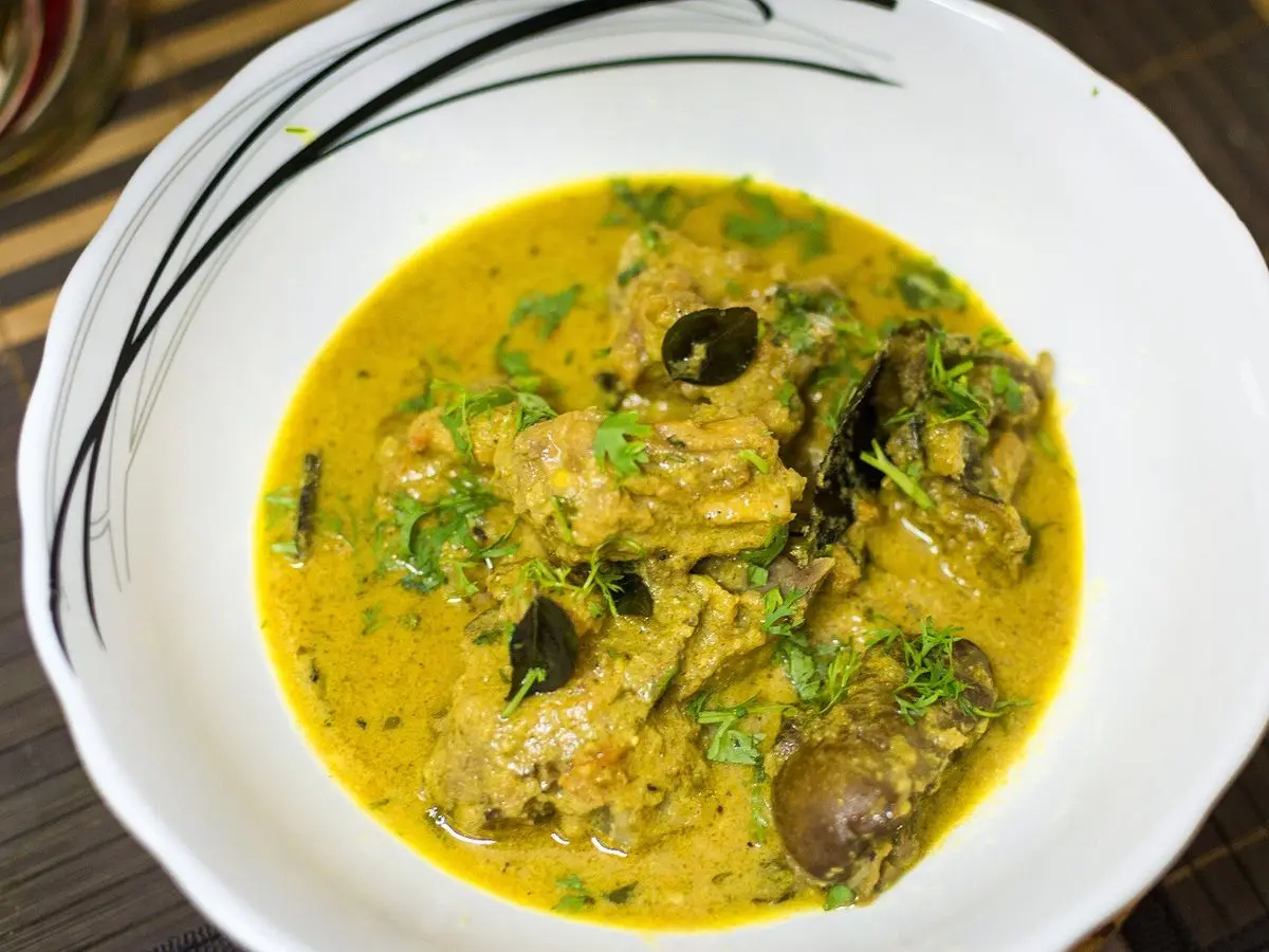 Plato blanco de pescado en salsa amarillo verdosa con cilantro picado y chiles