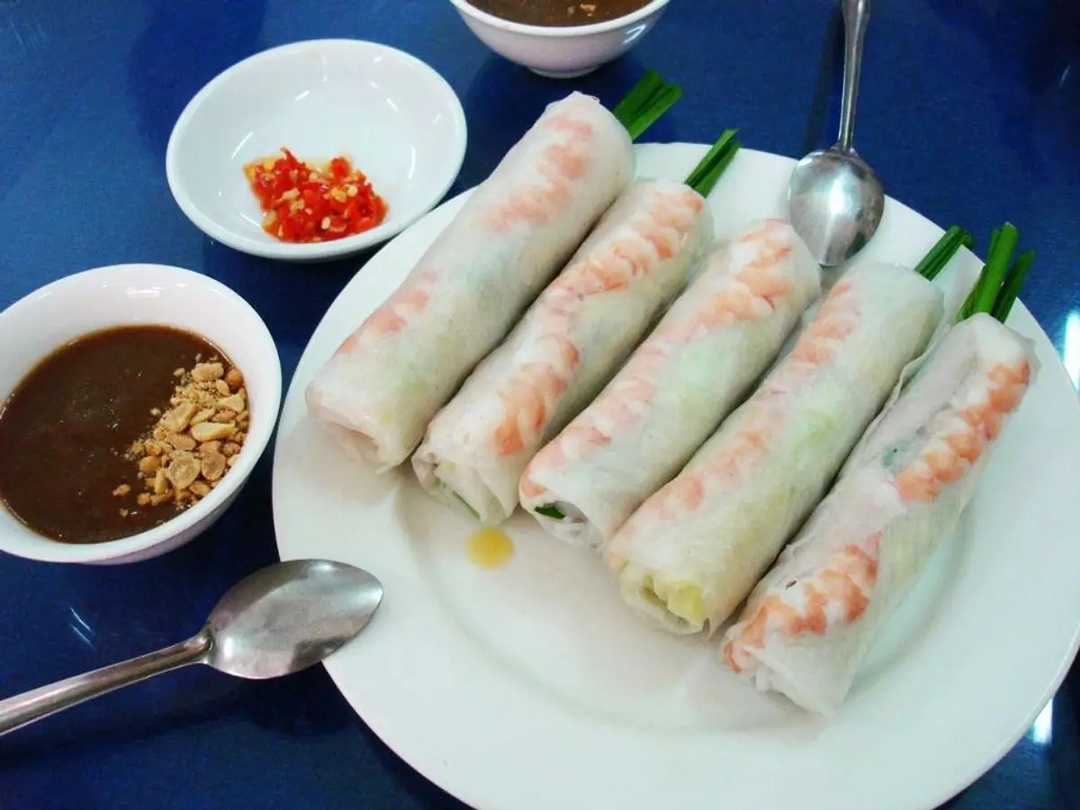 Plato con rollitos frescos de papel de arroz rellenos de langostino, con salsa oscura para mojar