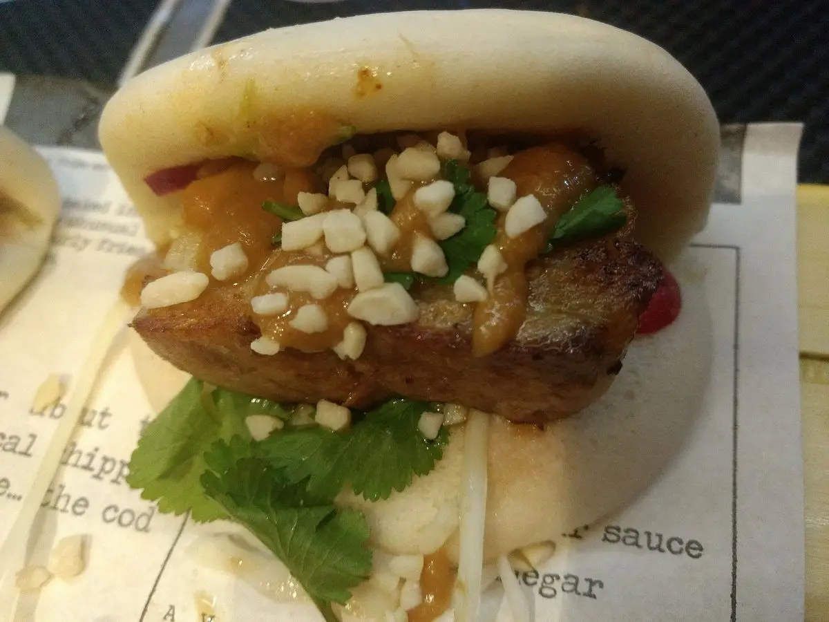 Panecillo bao al vapor relleno de cerdo guisado, cacahuete picado y hierbabuena