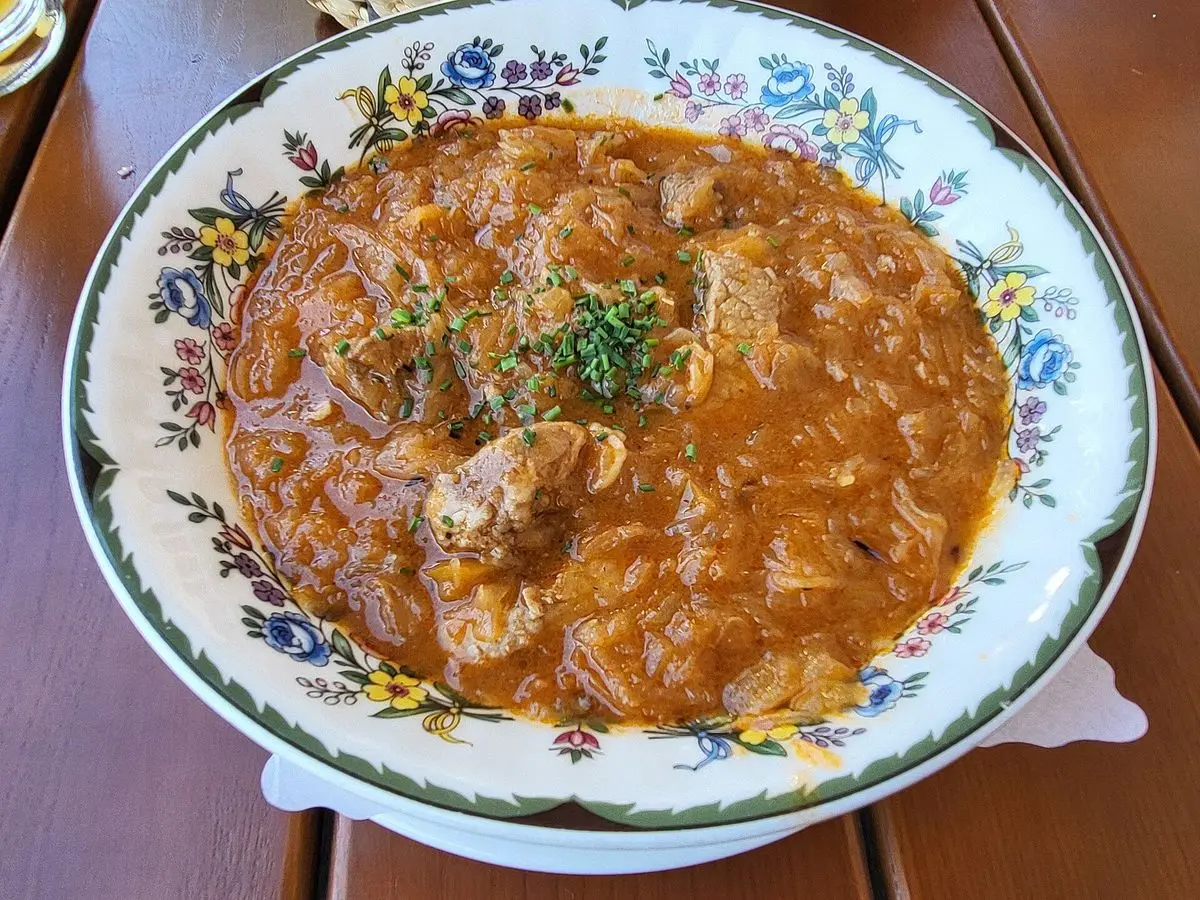 Gulasch de cerdo con chucrut y pimentón en una fuente de porcelana decorada