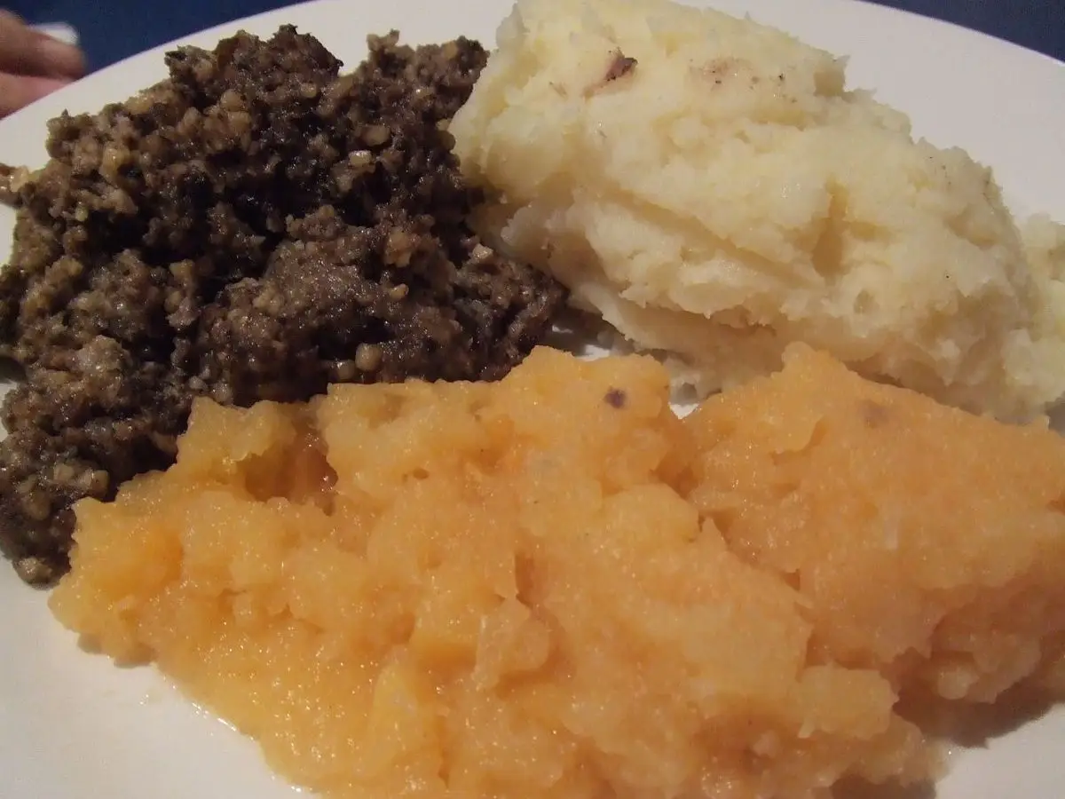 Plato con haggis oscuro, puré de nabo anaranjado y puré de patata