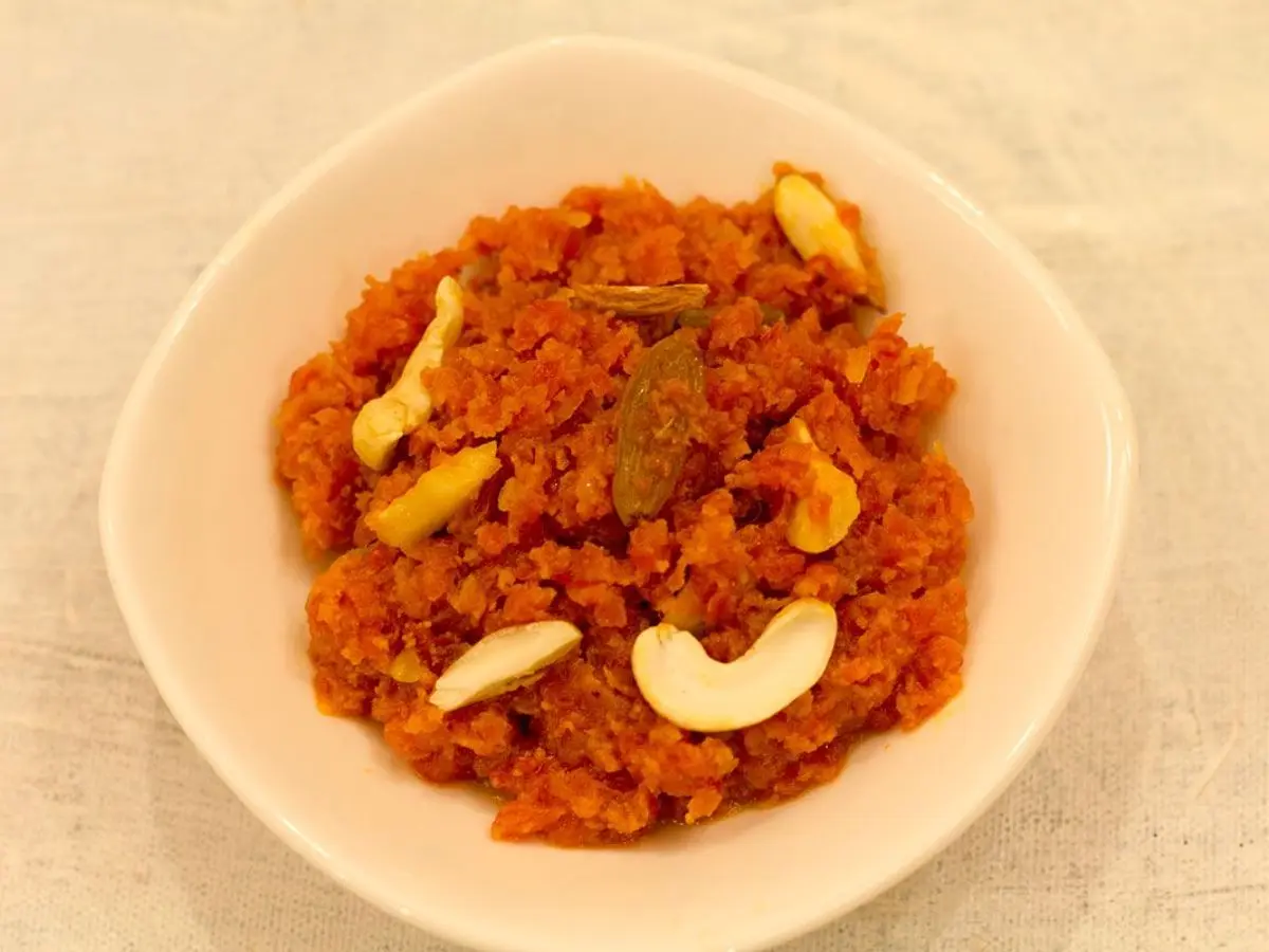 Cuenco blanco con halwa naranja de zanahoria decorado con anacardos y pistachos