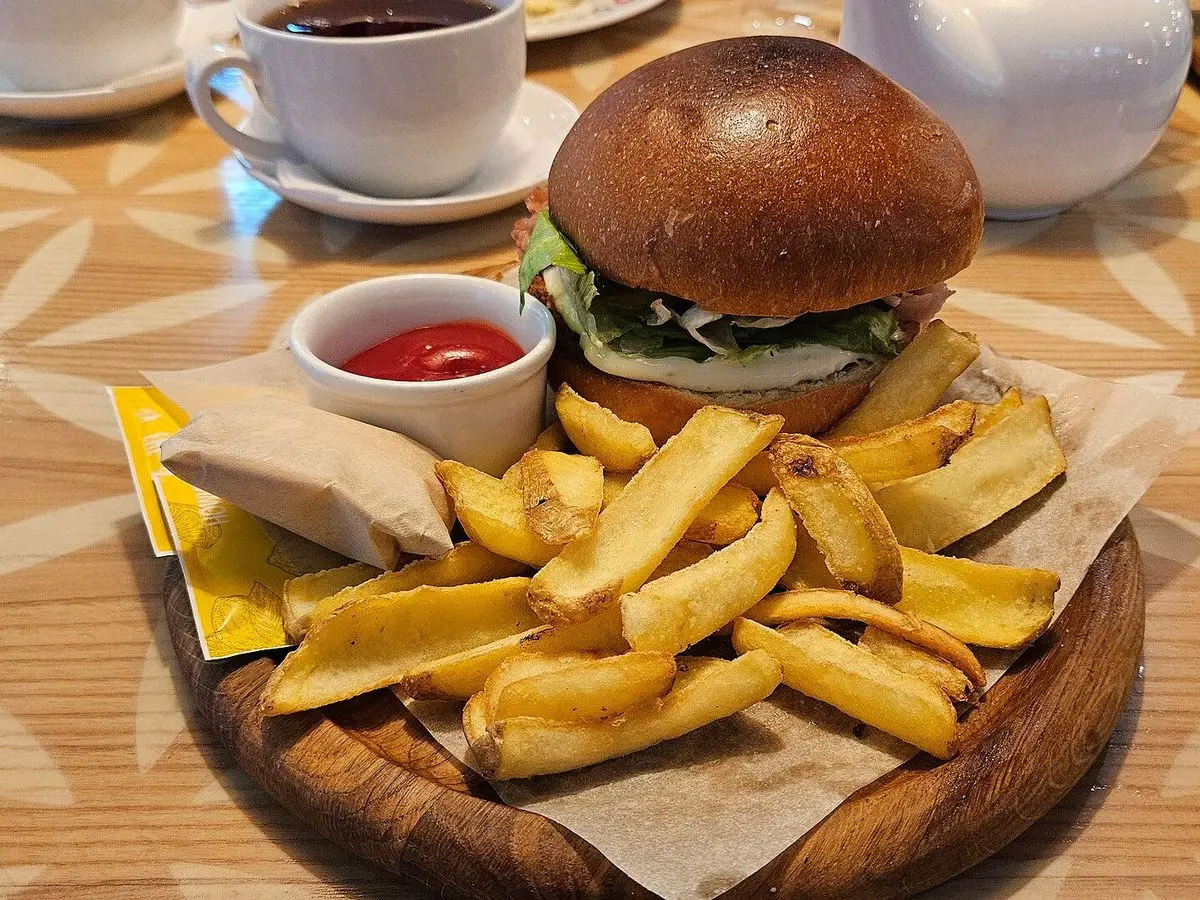 Hamburguesa de carne con lechuga y pan brioche sobre una tabla de madera con patatas fritas