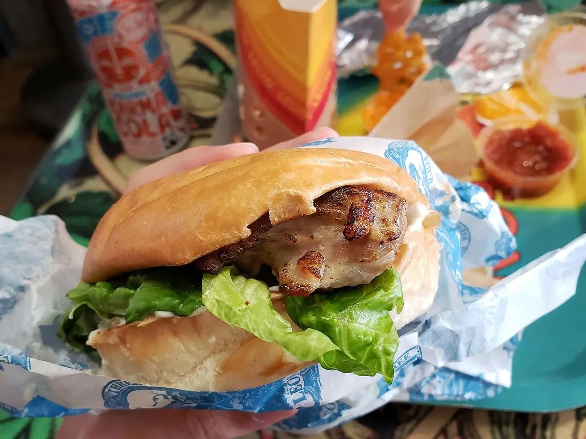Hamburguesa de pollo a la plancha con lechuga en un pan de hamburguesa, envuelta en papel