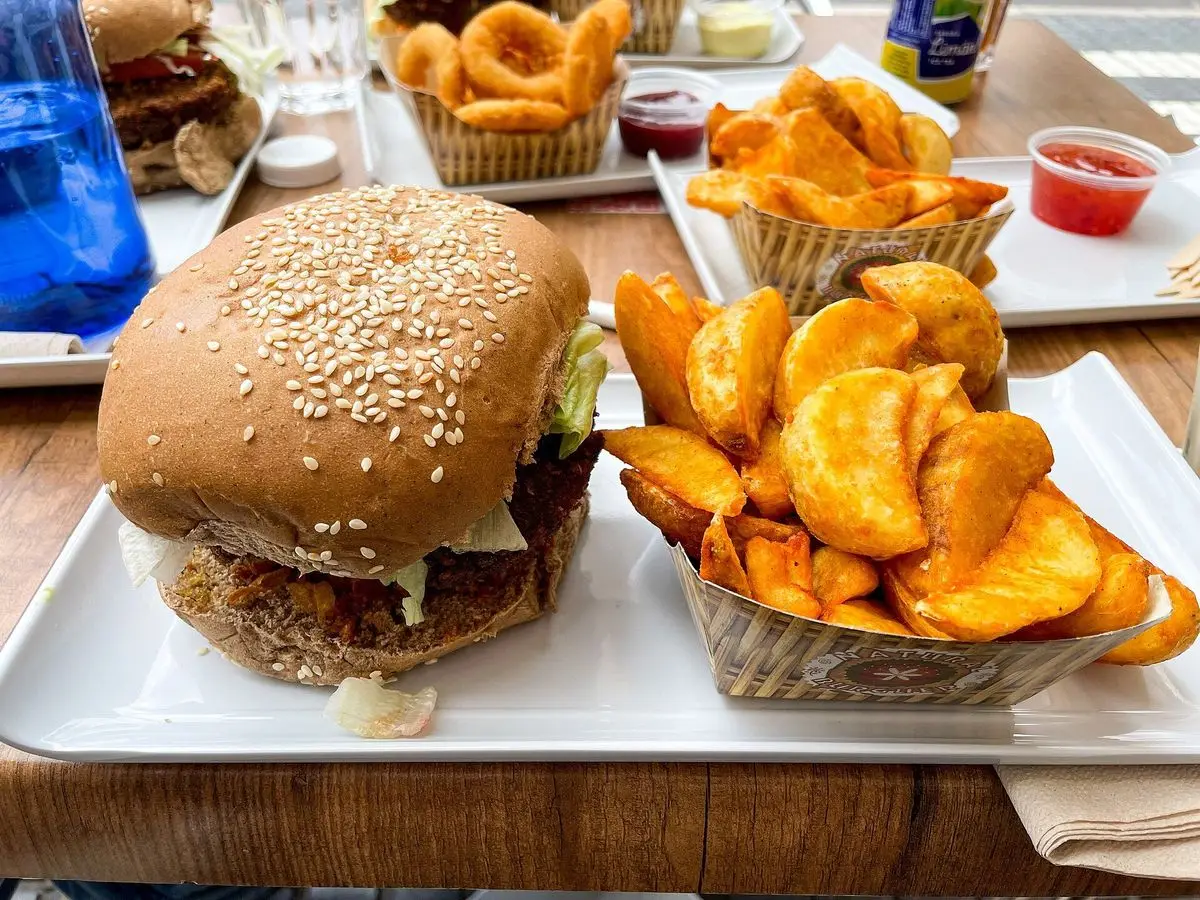 Hamburguesa con pan de sésamo y cesta de patatas gajo doradas